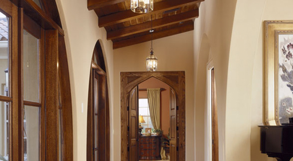 An arched hallway with exposed wood beams and lantern light