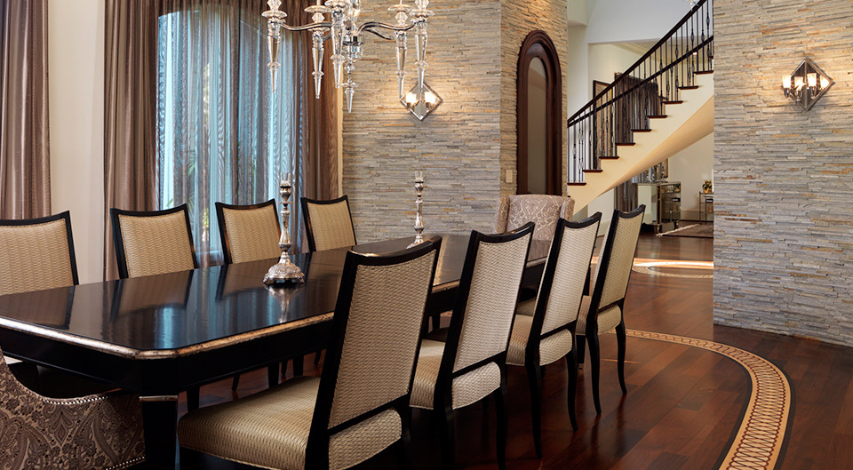 A formal dining room with stacked stone and a curved stair