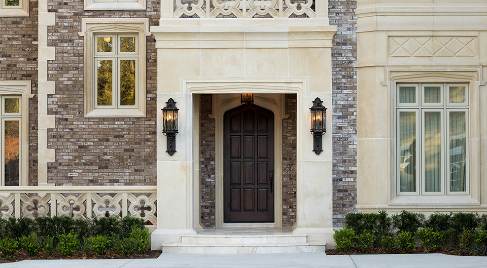 A limestone and brick entry with a carved arch and a wood door